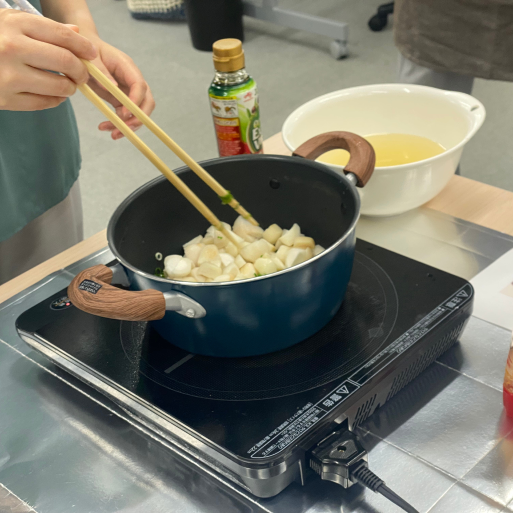 IHコンロにかけた鍋で、食材を菜箸で炒めている手元