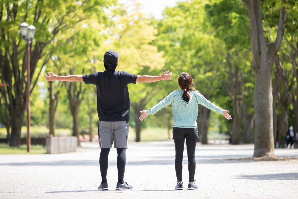 公園で、2人が両腕を広げて体を伸ばしている様子