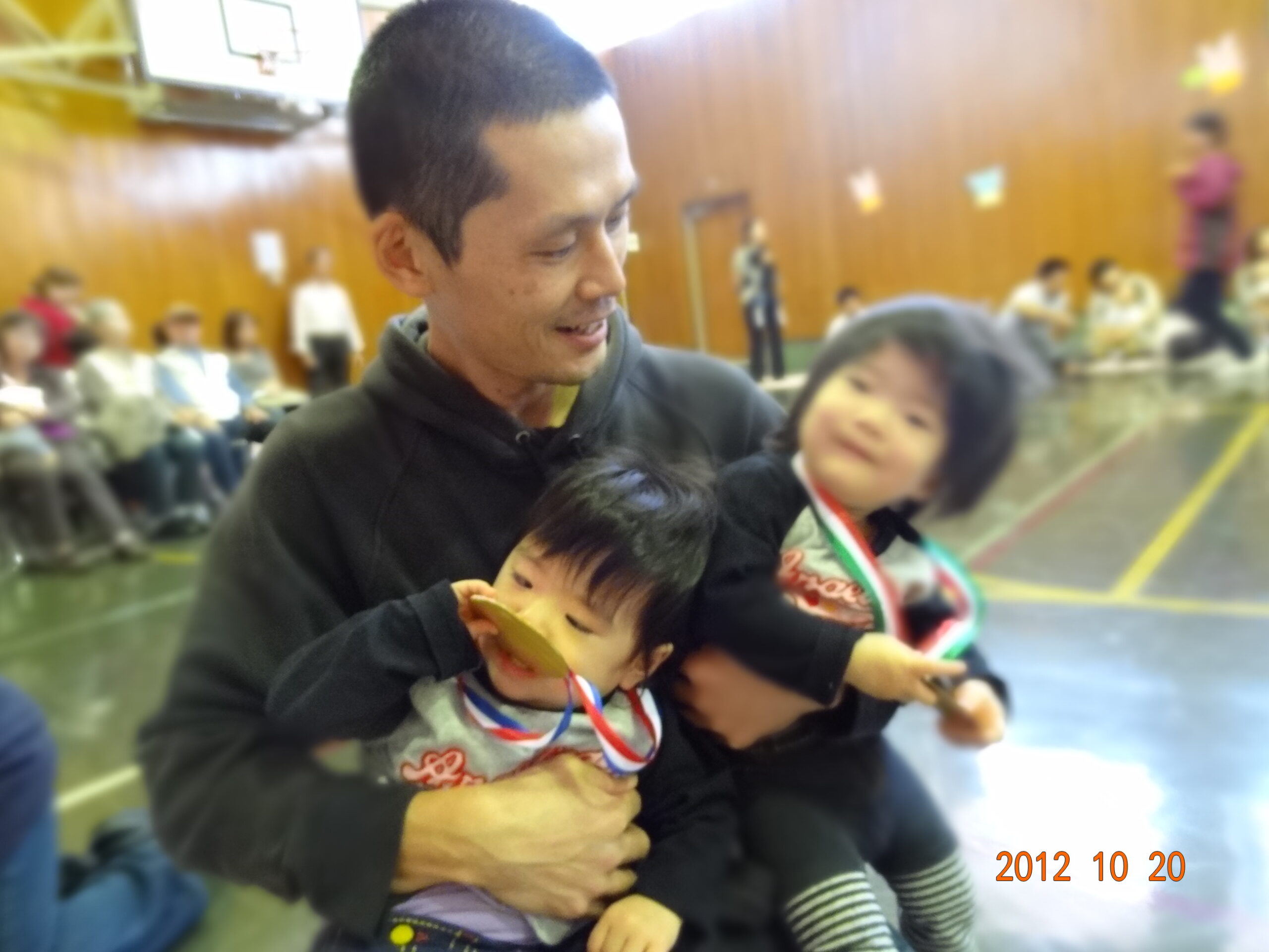 メダルをかけた双子の娘たちを抱く田村（2012年）